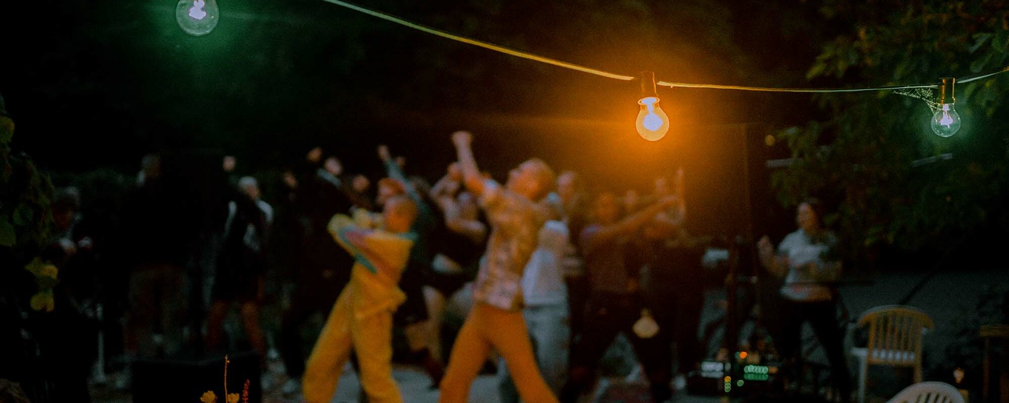 Lichterkette im Vordergrund und Menschen tanzen